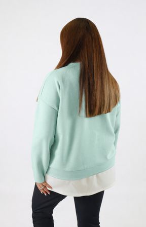 Woman wearing a navy sweatshirt with a white trim on a plain background