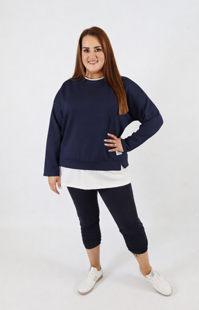 Woman wearing a navy sweatshirt with a white trim on a plain background