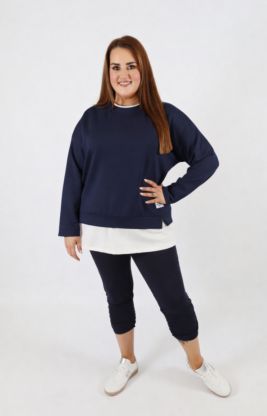 Woman wearing a navy sweatshirt with a white trim on a plain background
