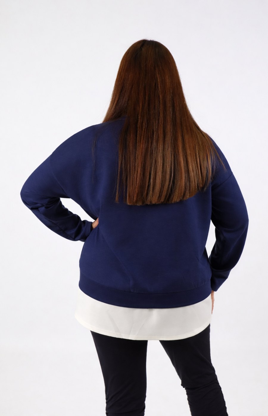 Woman wearing a navy sweatshirt with a white trim on a plain background