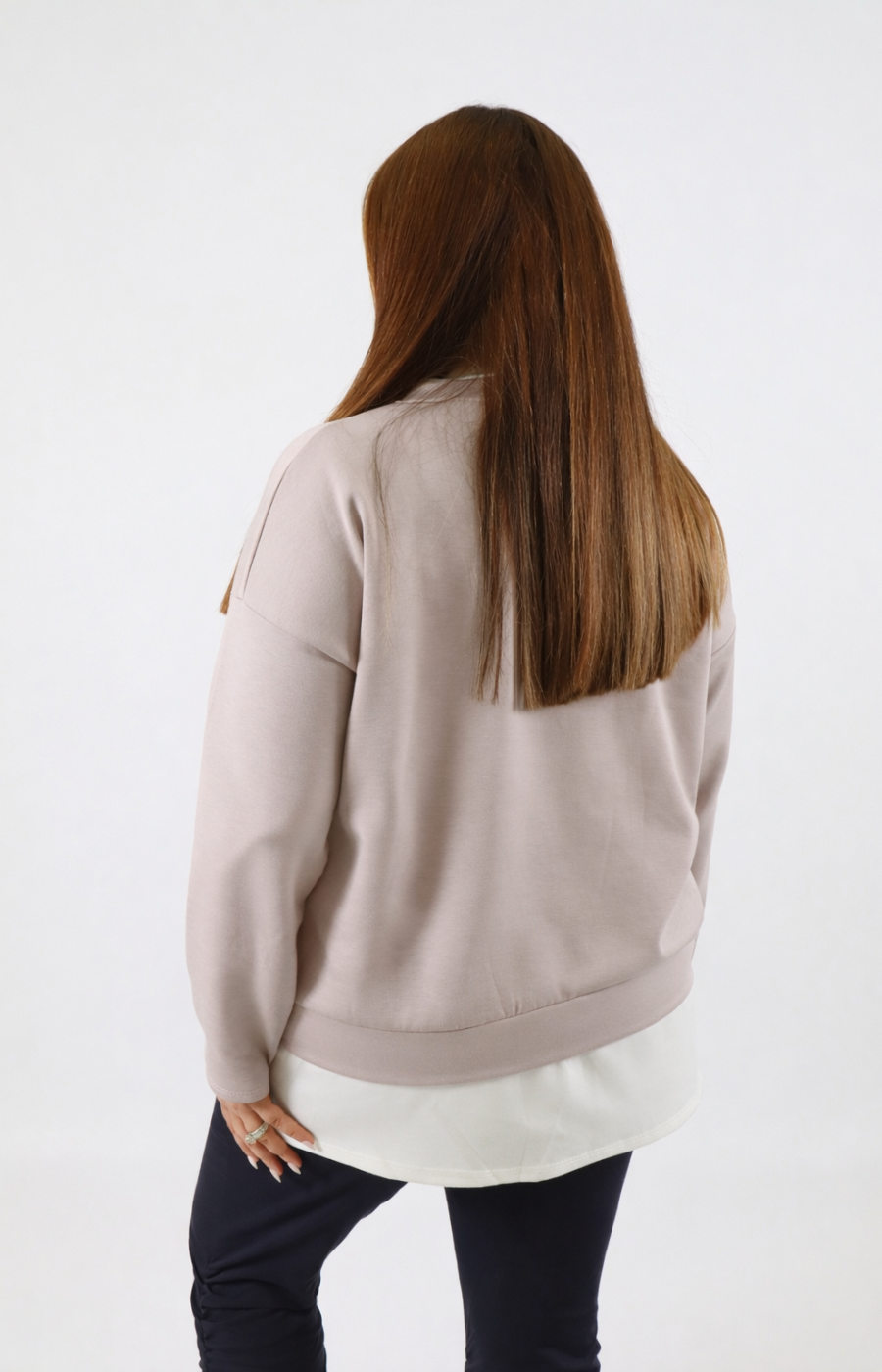 Woman wearing a taupe sweatshirt with a white trim on a plain background