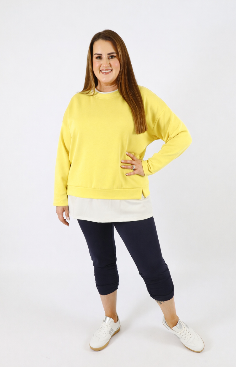Woman wearing a yellow sweatshirt with a white trim on a plain background