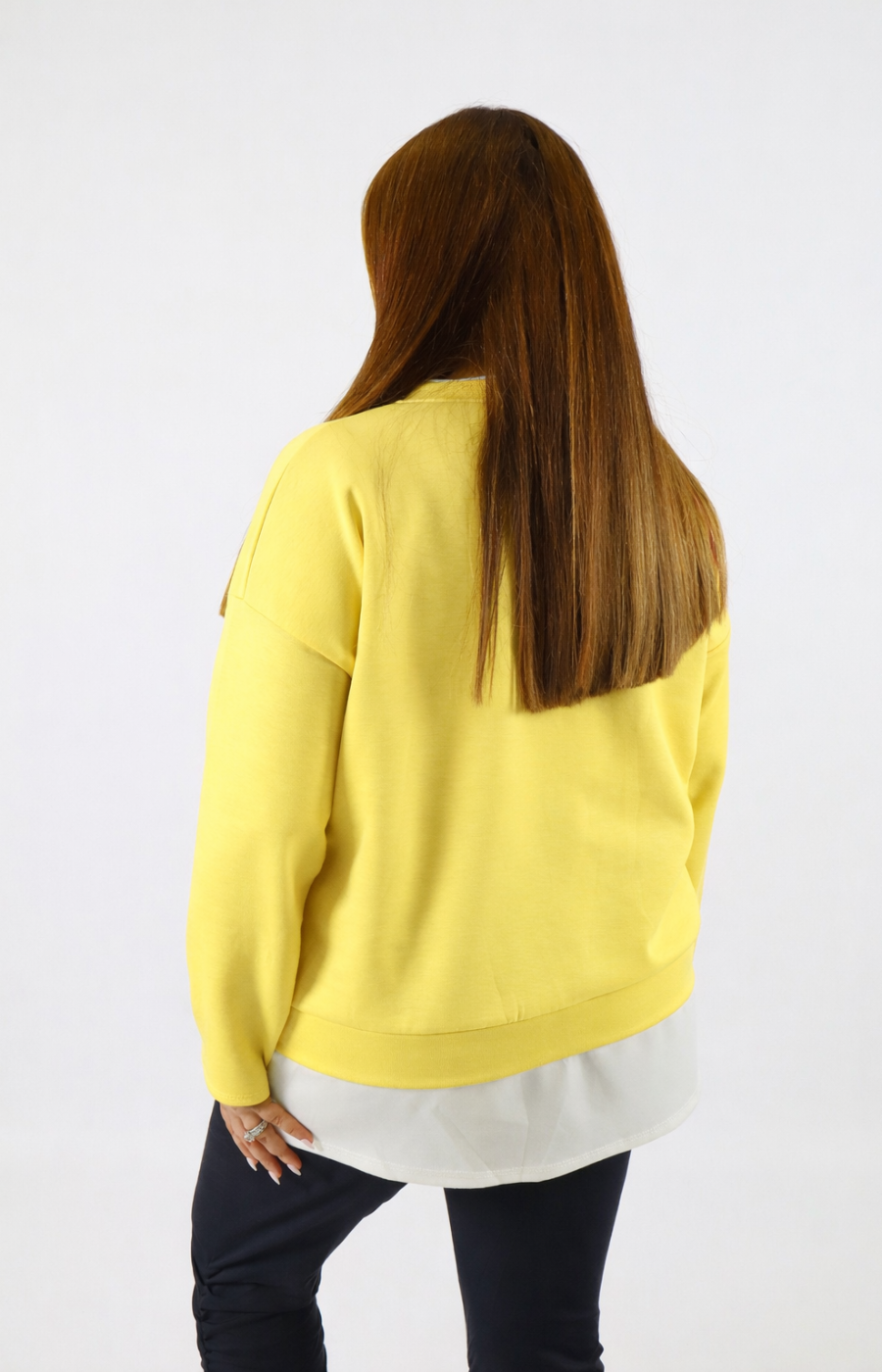 Woman wearing a yellow sweatshirt with a white trim on a plain background