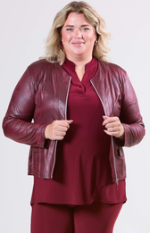 Woman wearing a burgundy leather jacket and matching outfit on a white background