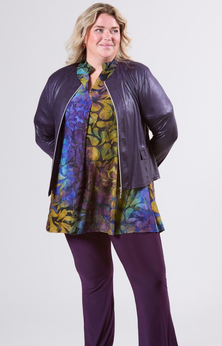 Woman wearing the purple magna jacket with an open zip, long sleeves and a round neck, over a colourful top 
