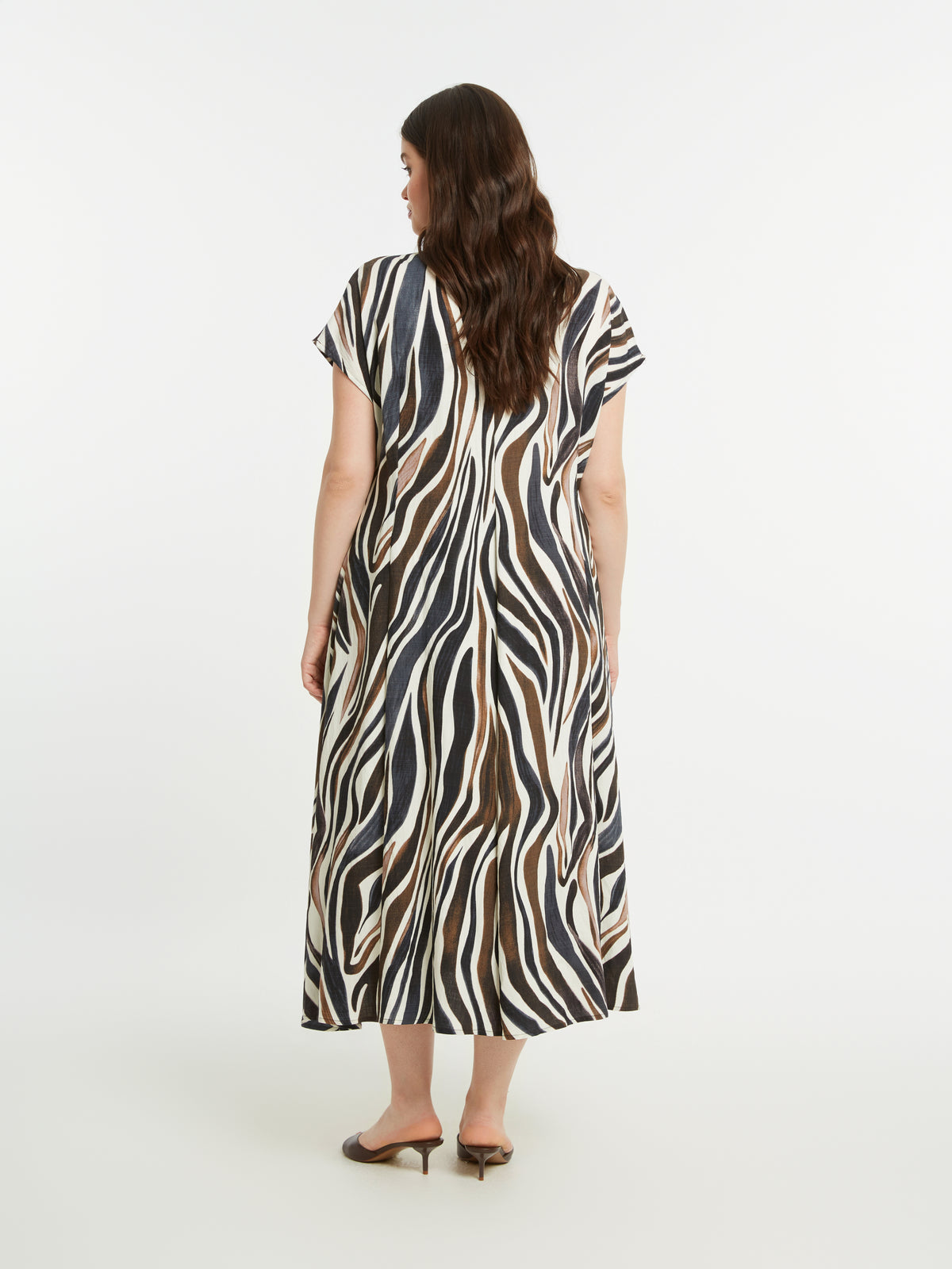 Woman wearing the Mat Animal Print Dress, a zebra print midi dress with an A-line shape on a white background