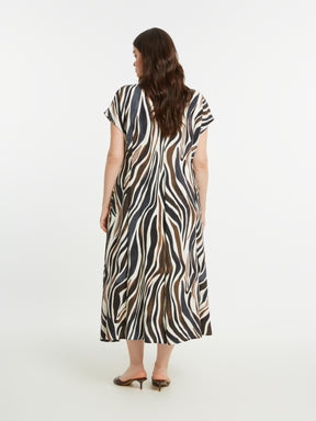 Woman wearing the Mat Animal Print Dress, a zebra print midi dress with an A-line shape on a white background