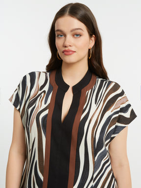 Woman wearing the Mat Animal Print Dress, a zebra print dress with short sleeves and a V neckline with a plain background