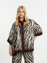 Woman wearing the Mat Animal Print Shirt a zebra print outfit with a brown and black trim on a white background