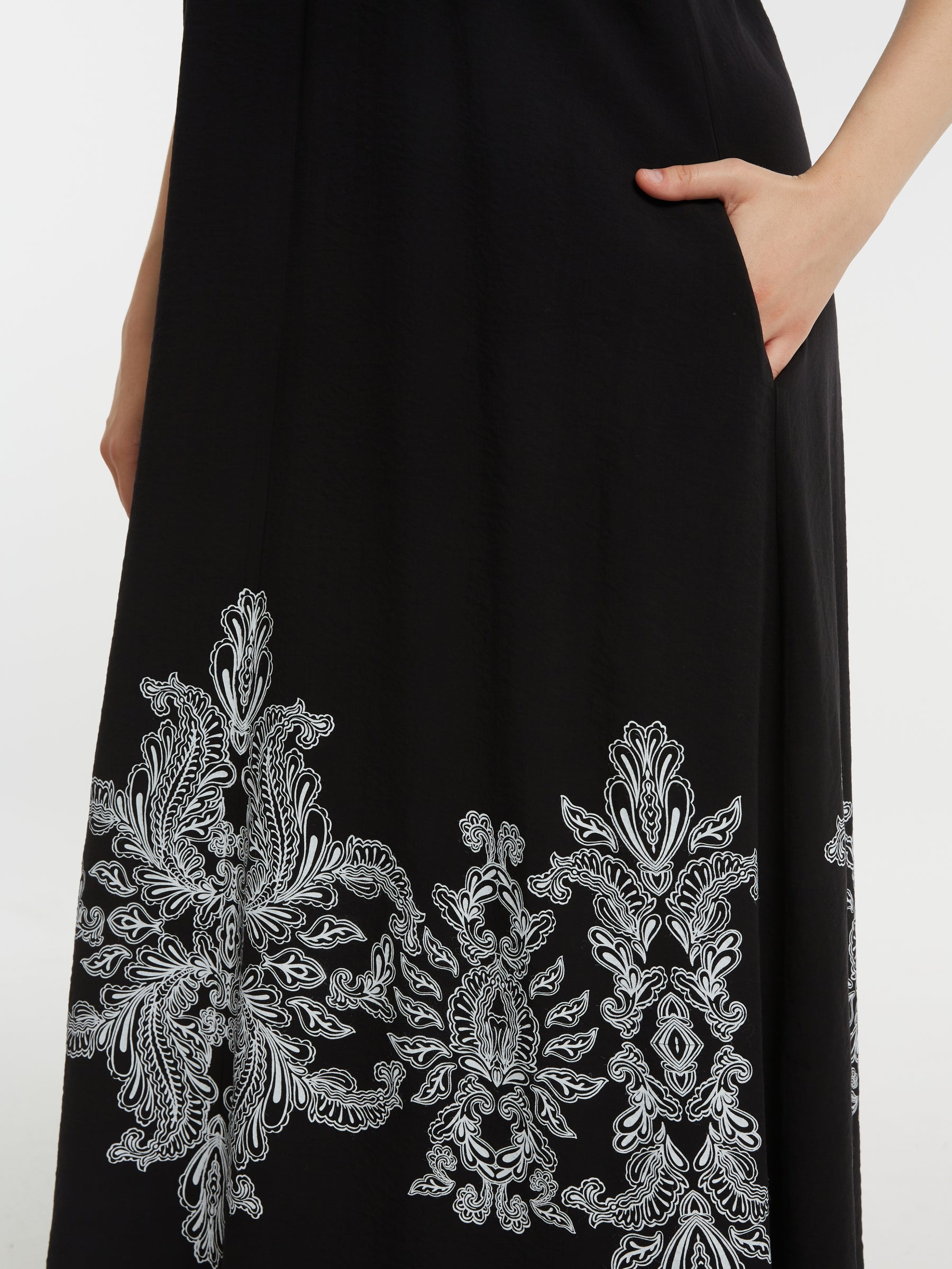 Mat Black Dress with Paisley Print, a Black dress with white embroidery, with and in side pocket on a white background