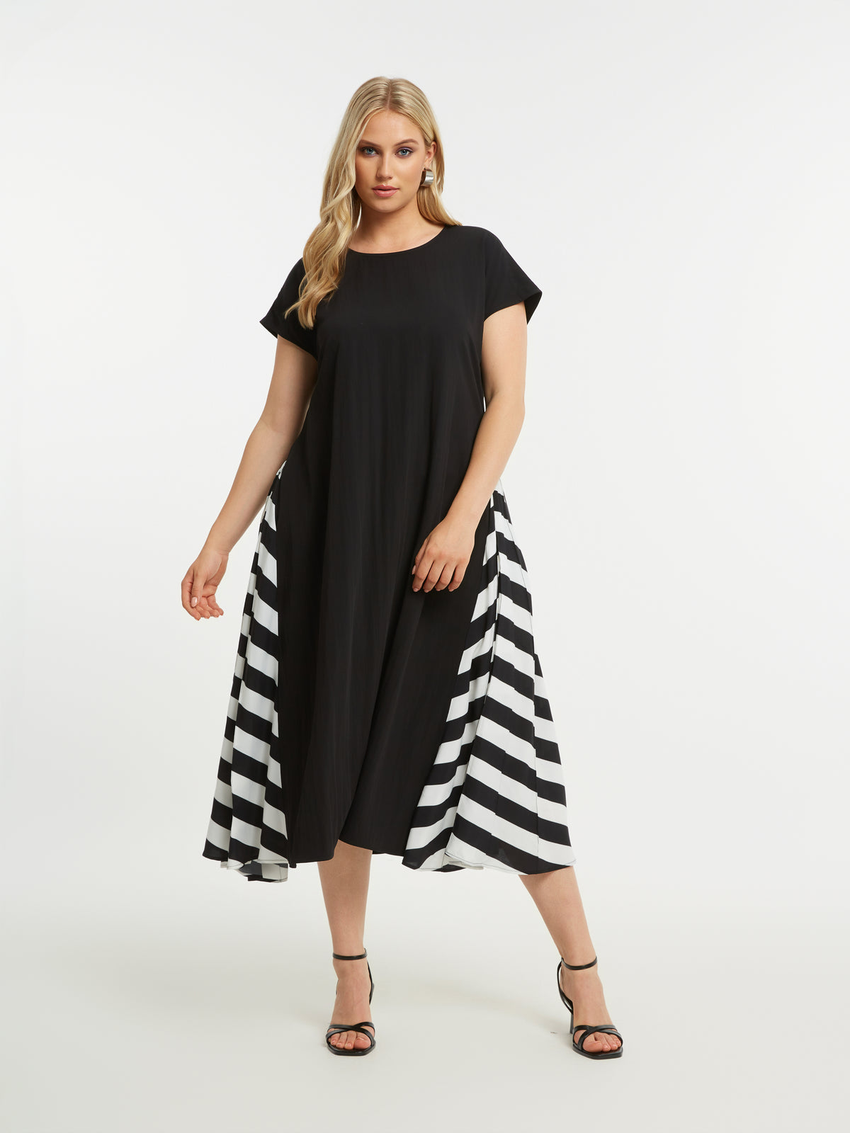 Woman wearing the Mat Black Dress with Side Stripes, a black midi dress with a striped pattern on each side, round neckline and short sleeves on a white background