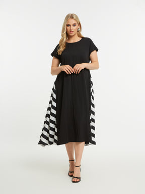 Woman wearing the Mat Black Dress with Side Stripes, a black A-line midi dress with a round neckline and short sleeves and pockets. It also has a striped pattern on a white background