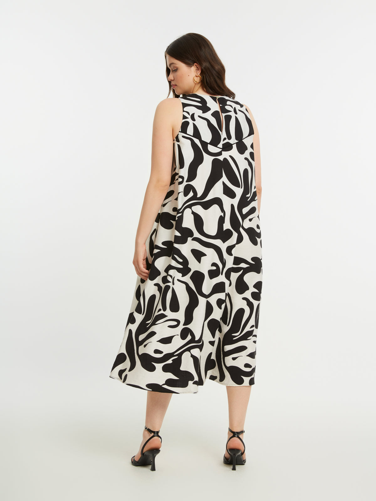 Woman wearing the Mat Black and White Swirl Dress, a black and white abstract patterned dress with an A-line shape on a white background