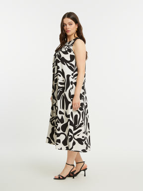 Woman wearing the Mat Black and White Swirl Dress, a sleeveless black and white patterned dress with an A-line shape and a round neckline on a white background