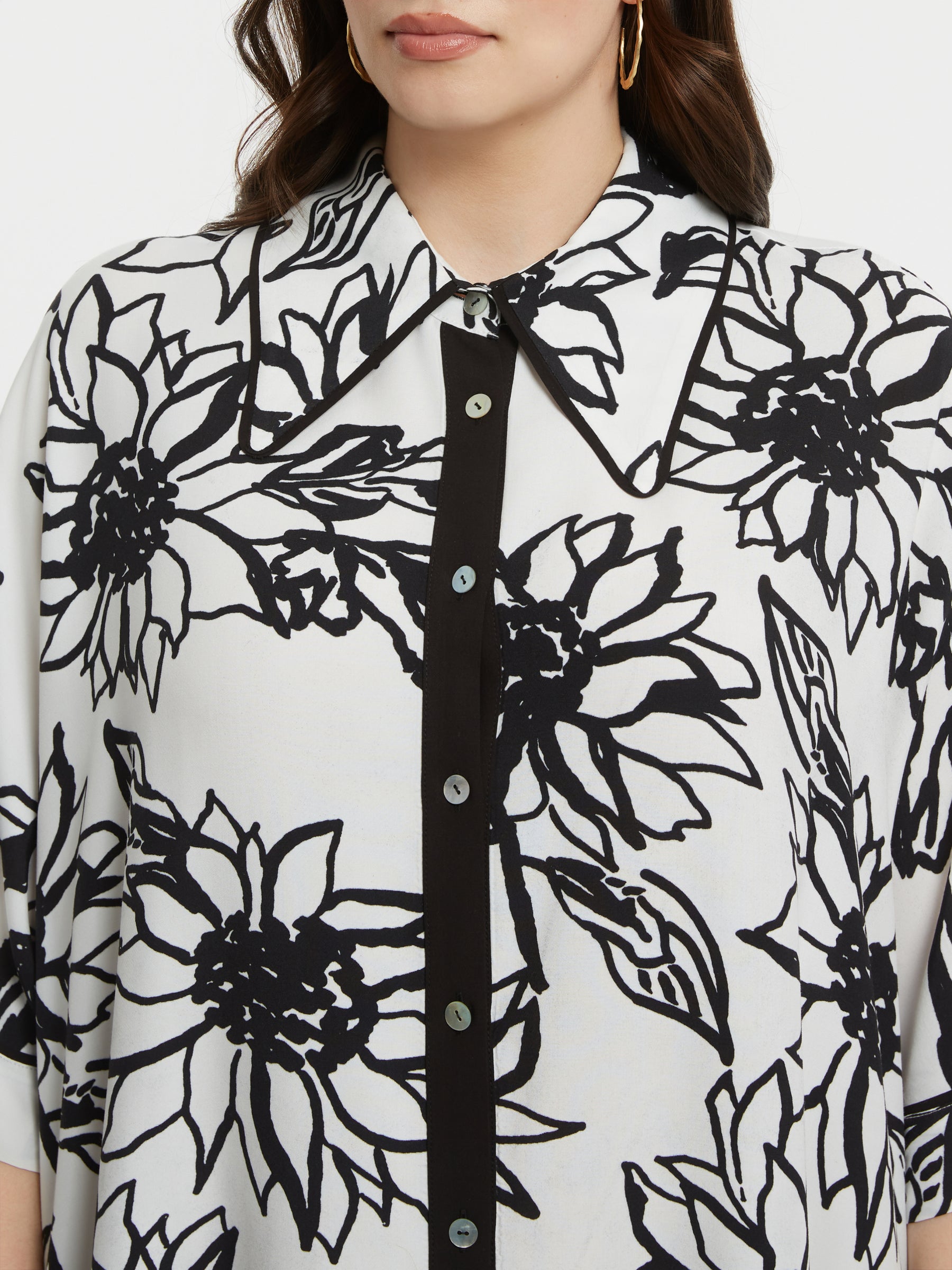 Person wearing a black and white floral patterned shirt with a close-up on the collar.