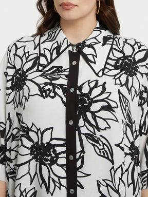 Person wearing a black and white floral patterned shirt with a close-up on the collar.
