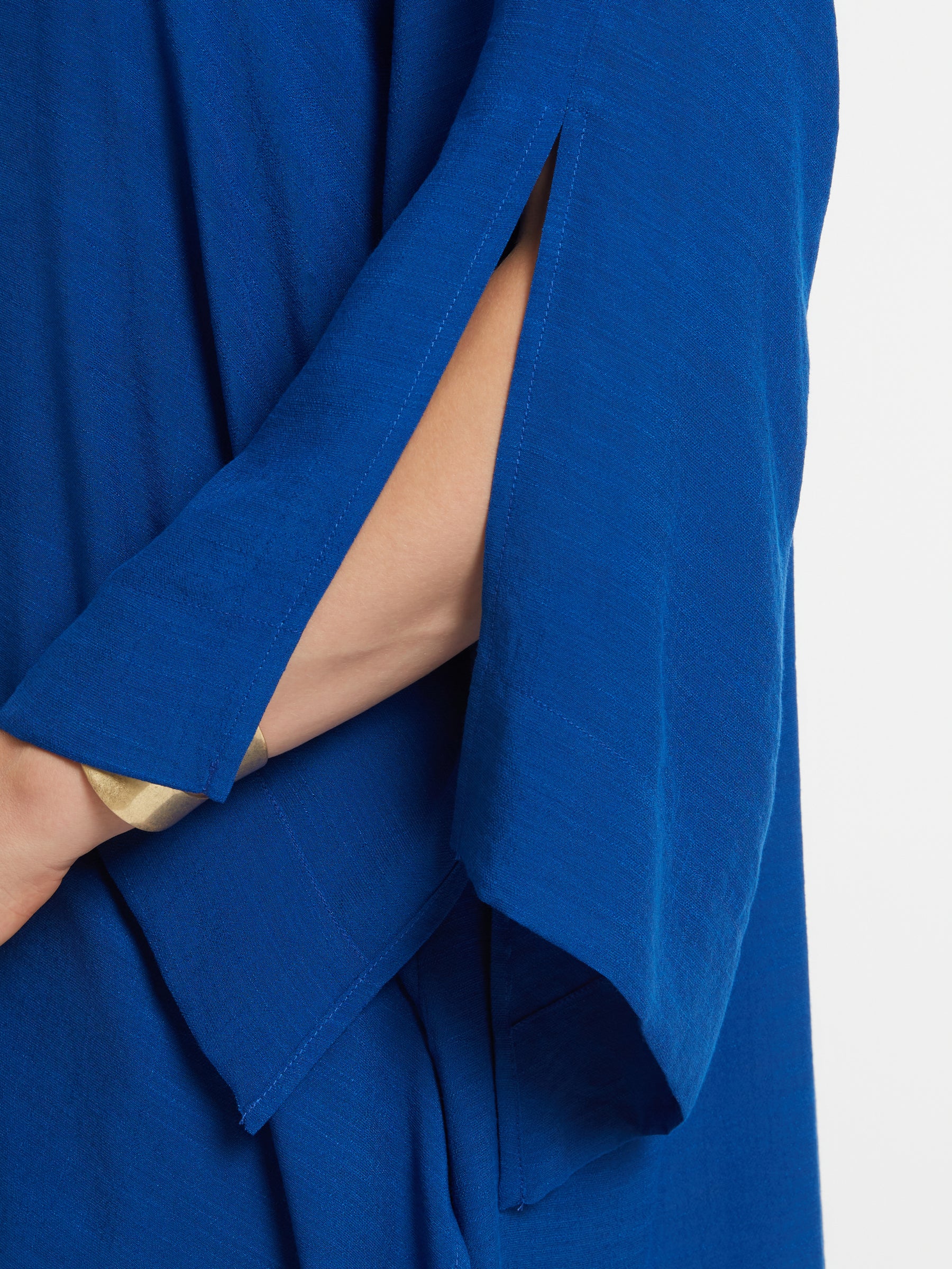 Close-up of the Mat Longline Tunic in Blue sleeve with a slit, showing skin underneath on a white background