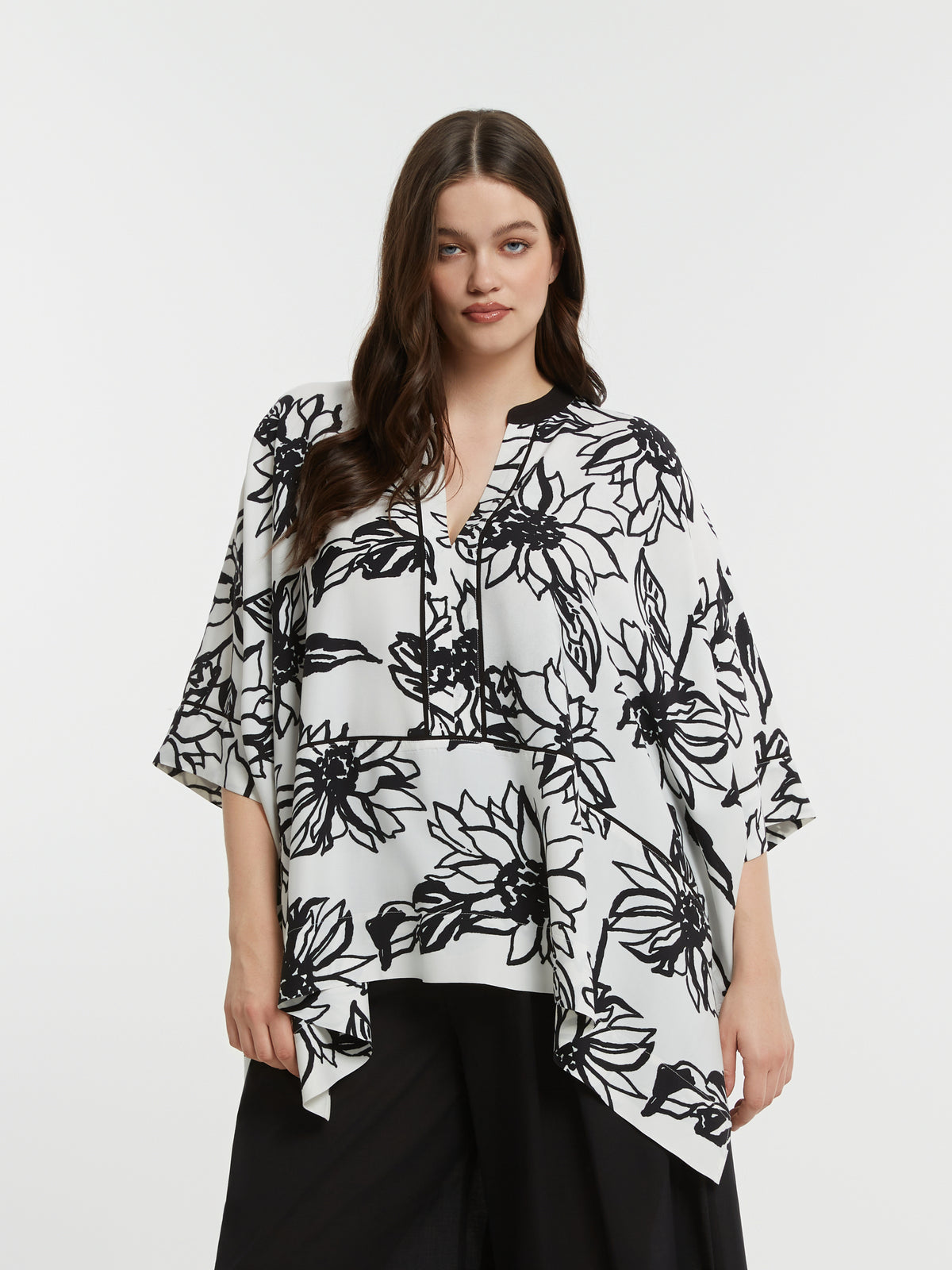 Woman wearing a black and white floral blouse against a white background