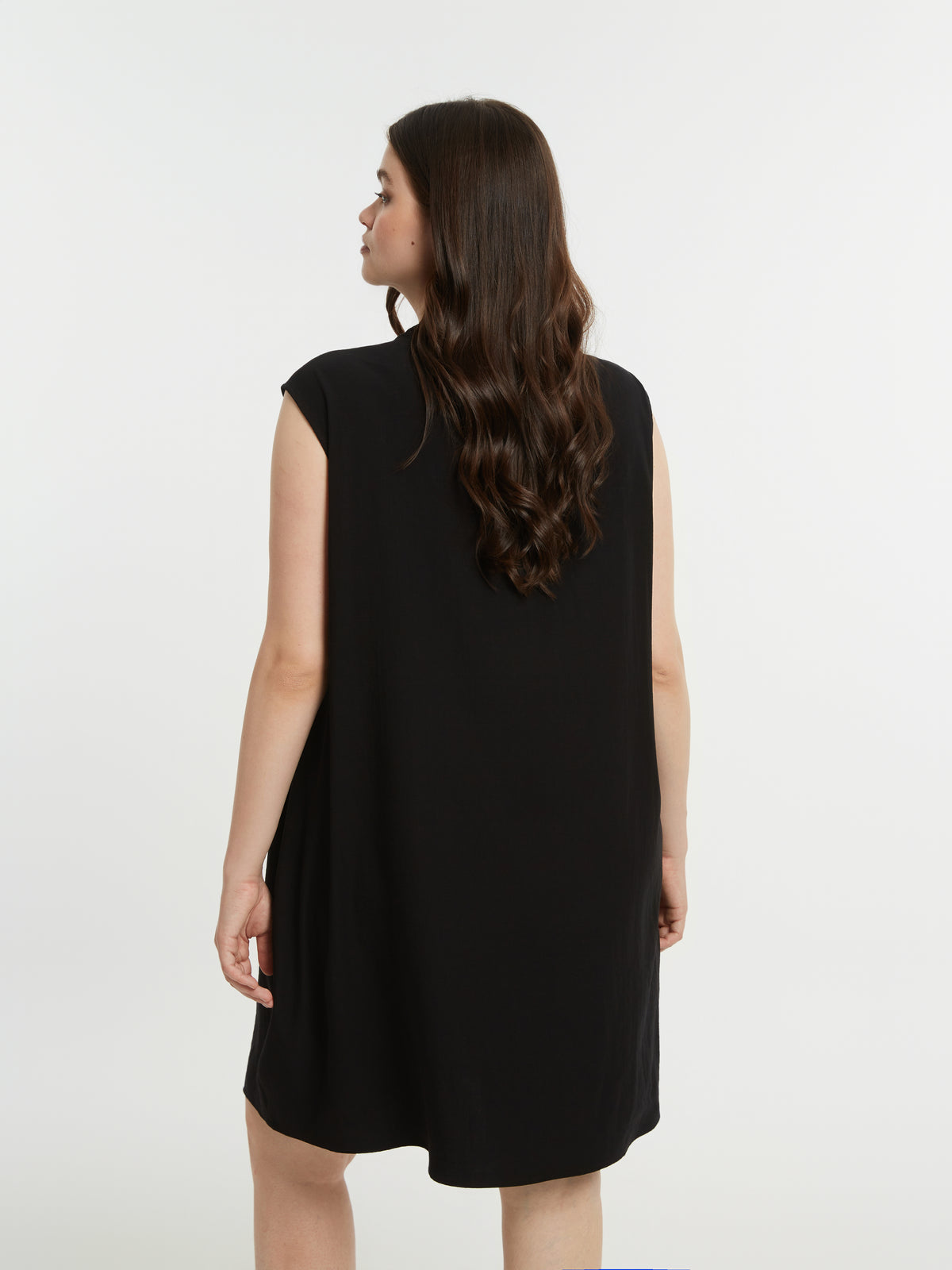 Woman wearing a black sleeveless dress against a white background