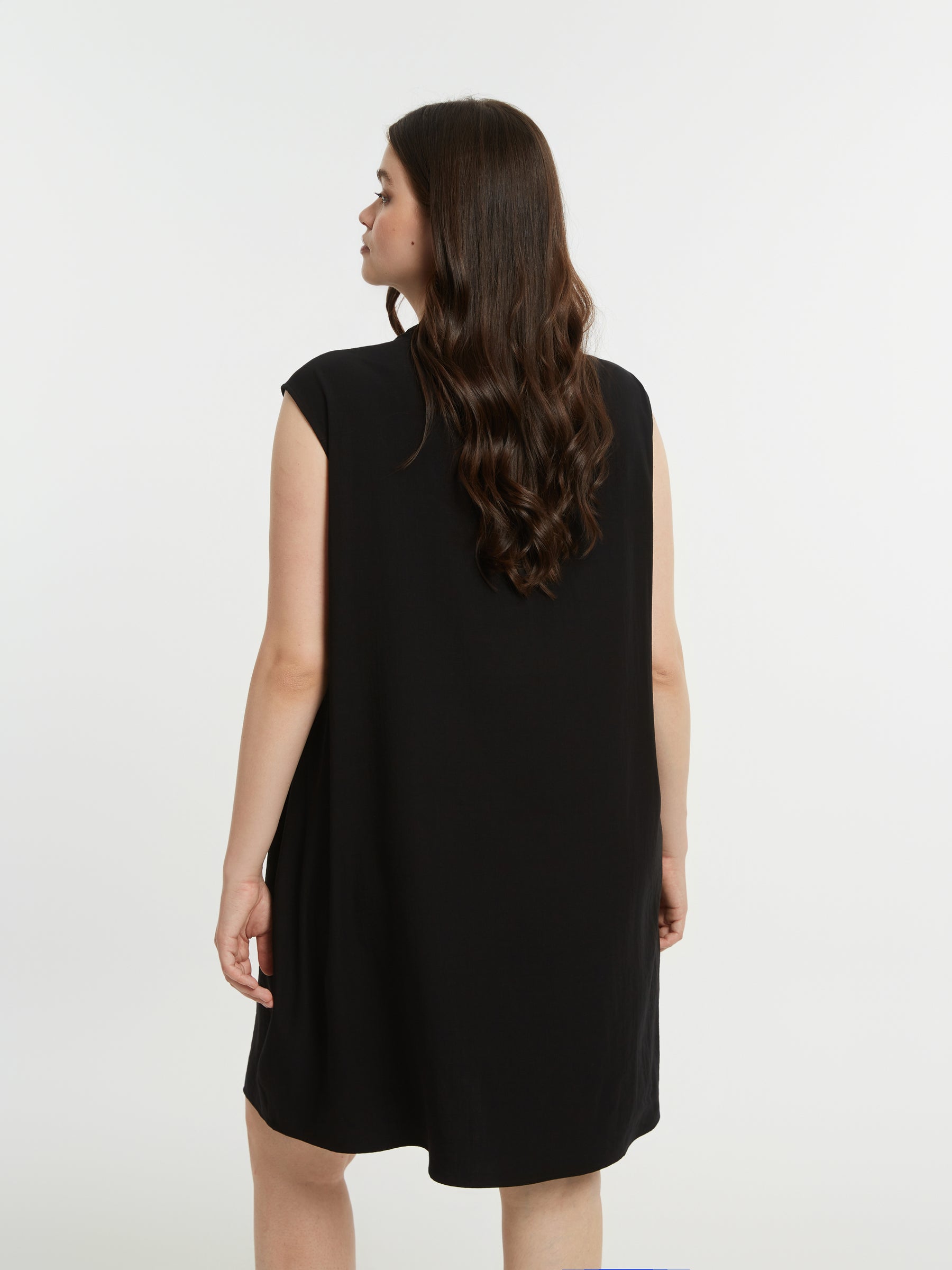 Woman wearing a black sleeveless dress against a white background