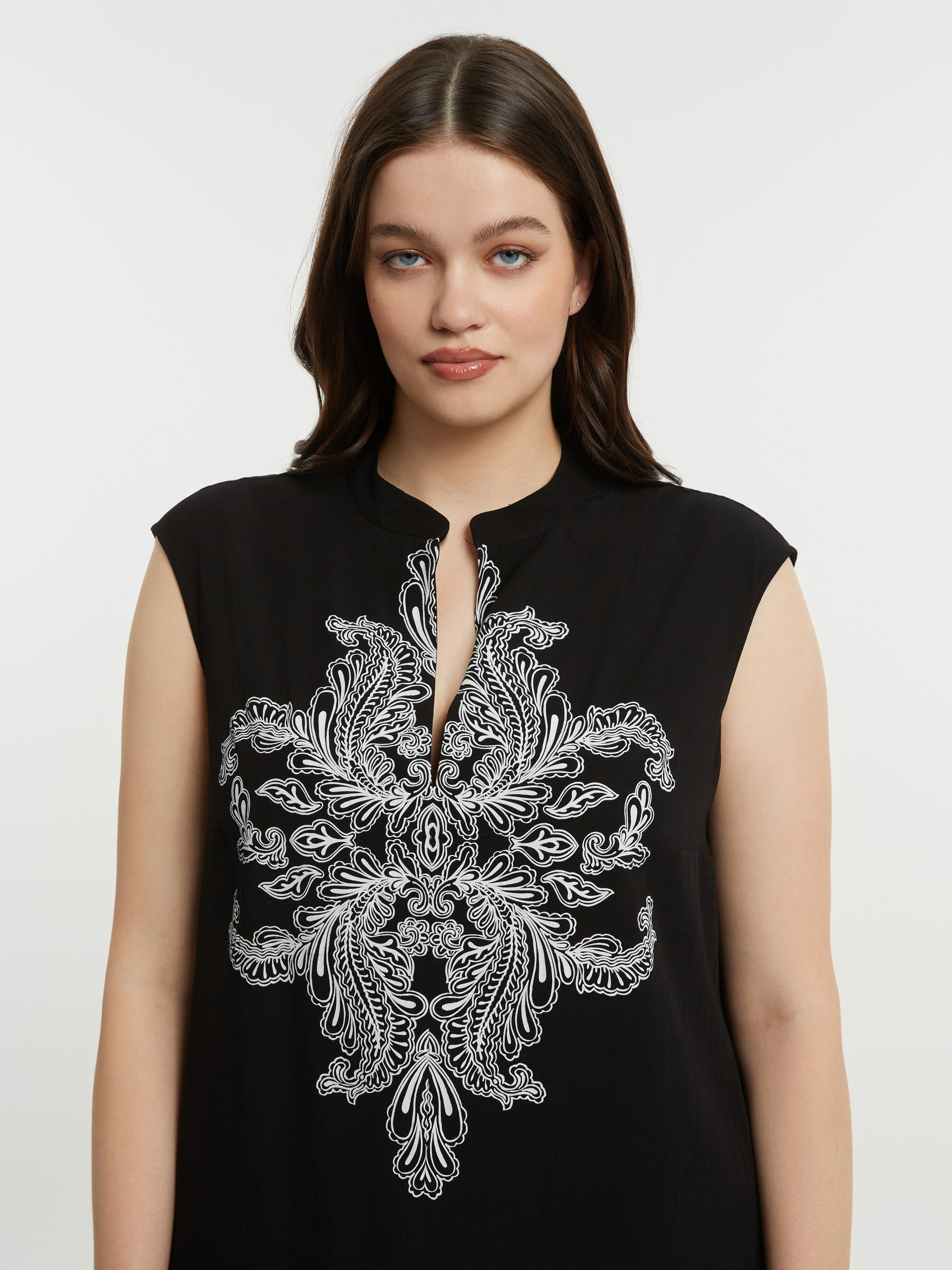 Women in a black dress with a V neckline, short sleeves and white embroidery detailing