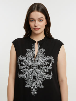 Women in a black dress with a V neckline, short sleeves and white embroidery detailing