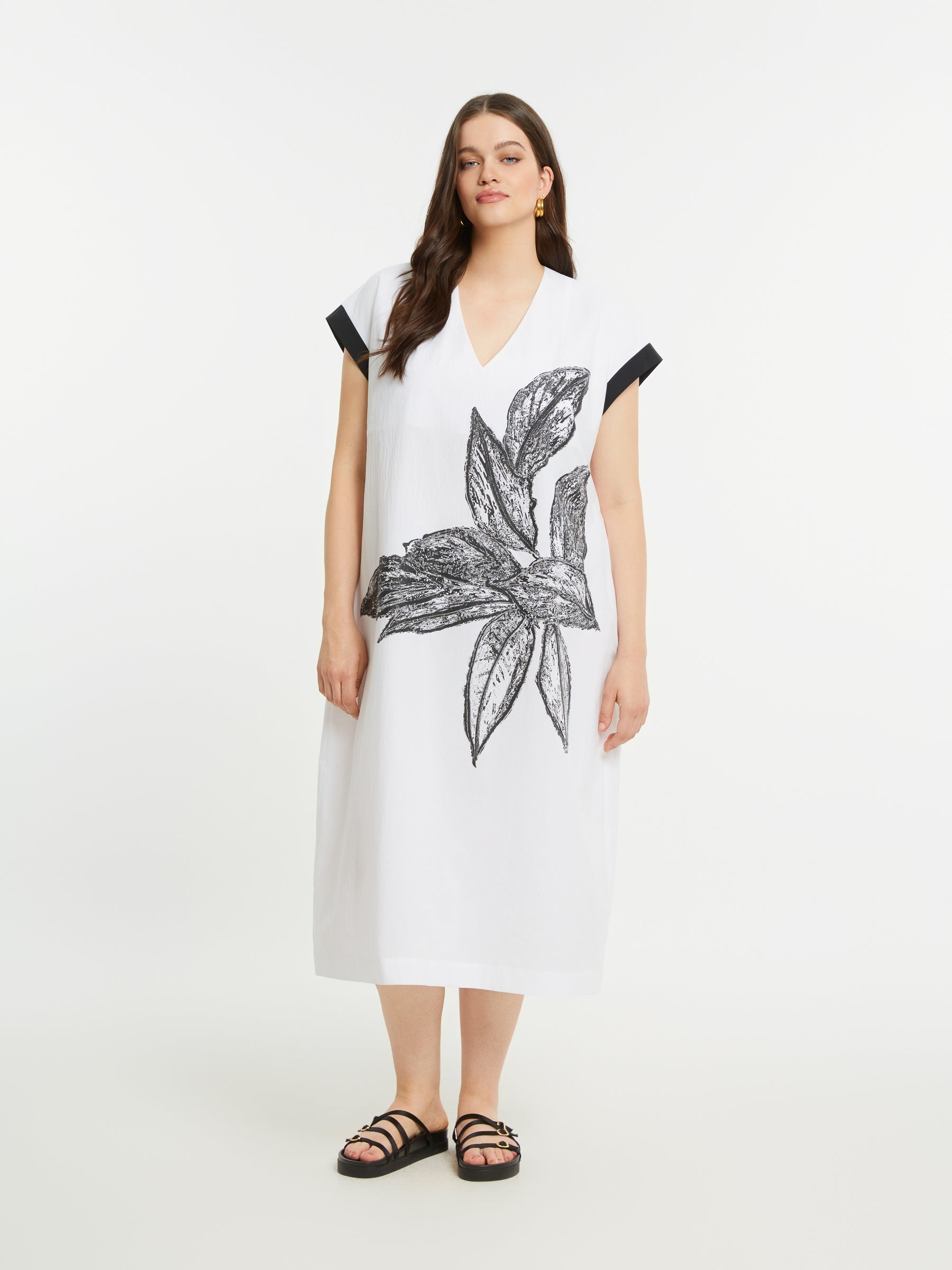 Woman wearing a white dress with black floral design on a white background
