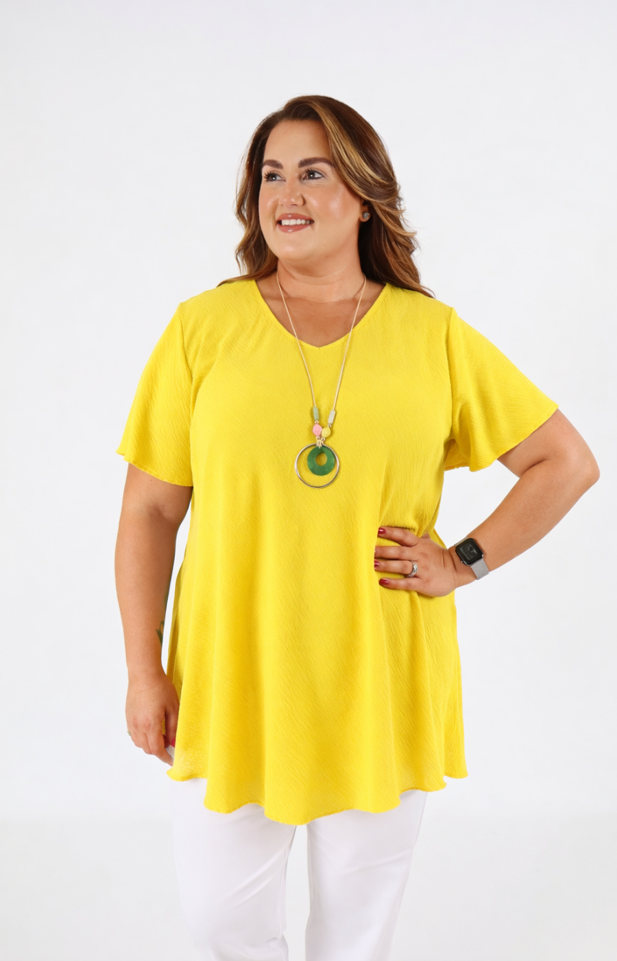 Woman wearing a yellow top and white pants on a white background