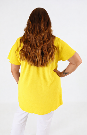 Person wearing a yellow shirt and white pants on a white background