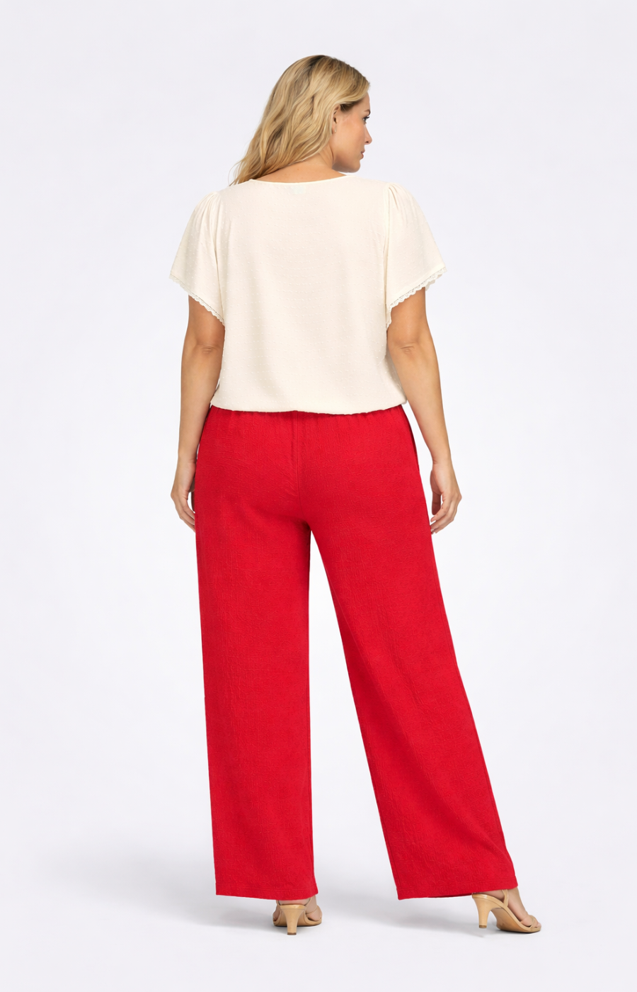 Woman wearing a beige top and red pants on a white background