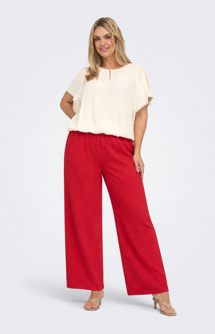 Woman wearing a white blouse and red pants on a white background