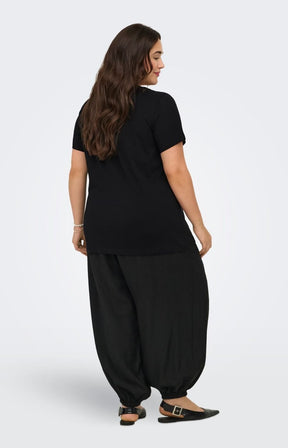 Woman wearing the Only Carmakoma Beau T-Shirt in Black with wide-leg pants on a white background. This image was created using AI.
