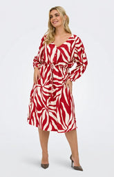 Woman wearing the Only Carmakoma Camille Dress in Red, red and white patterned V neck dress with long sleeves on a white background