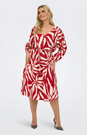 Woman wearing the Only Carmakoma Camille Dress in Red, red and white patterned V neck dress with long sleeves on a white background