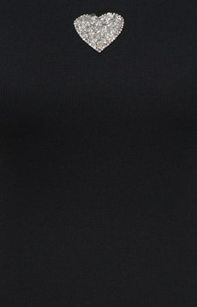 A close-up of the Only Carmakoma Iris Vest Top in Black, a black ribbed knit garment featuring a small, heart-shaped silver rhinestone heart near the neckline.