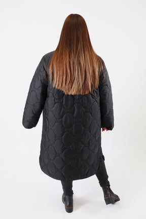 Person wearing a black coat with a plain background