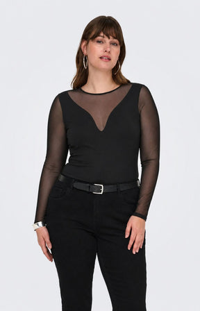 A woman modelling the Only Carmakoma Love Top in Black, a black long-sleeve top with sheer mesh sleeves and a V-neckline, paired with black pants and a black belt, against a light gray studio background.
