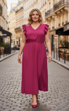 Woman in a wine coloured dress standing on a city street.