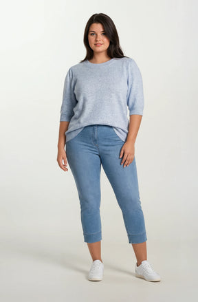 Woman wearing a light blue sweater and jeans on a white background