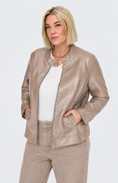 A woman modeling the Only Carmakoma Robber Faux Leather Jacket in Walnut, a light taupe faux-leather jacket with a zippered front, buttoned collar, and side pockets, paired with a white top and matching taupe pants against a light gray background. This image has be created using AI.
