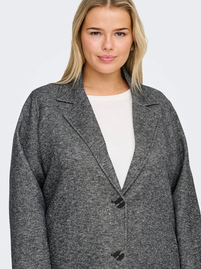 Woman wearing a gray coat over a white top on a plain background