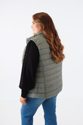 Person wearing a gray puffer vest on a white background