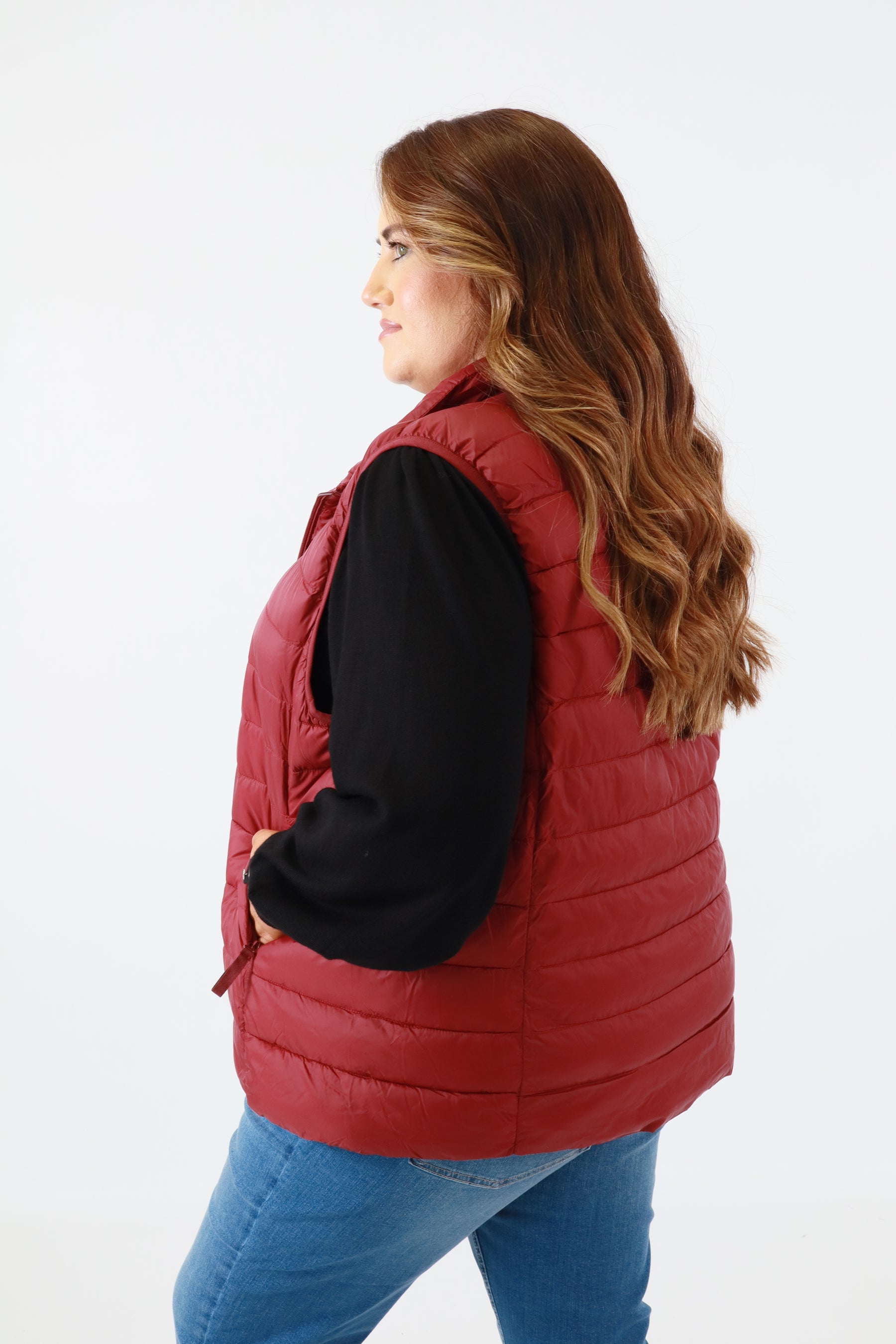 Person wearing a red puffer vest on a white background