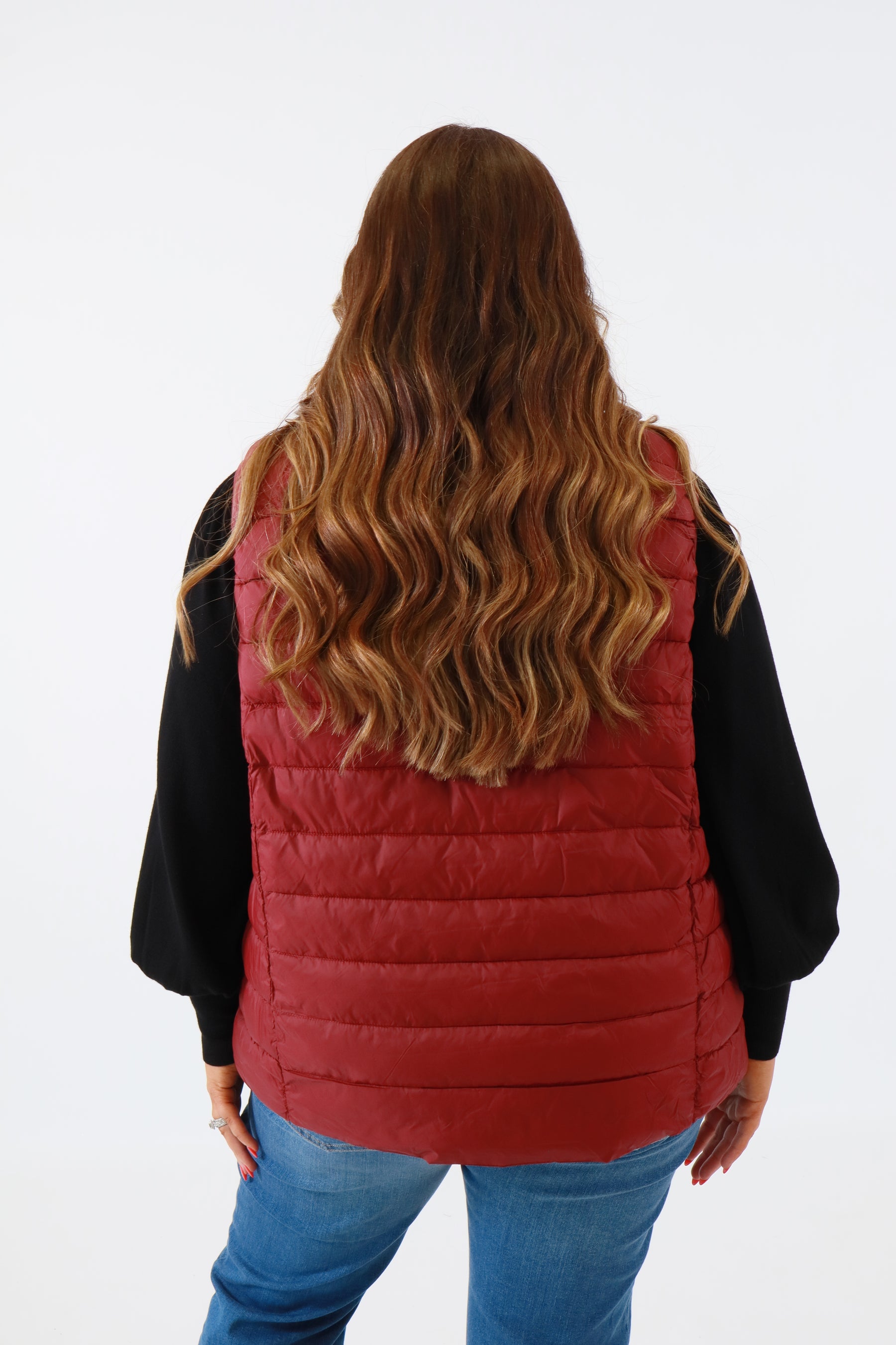 Person wearing a red quilted vest on a white background