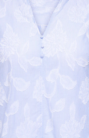 Light blue blouse with white floral pattern on a light blue background