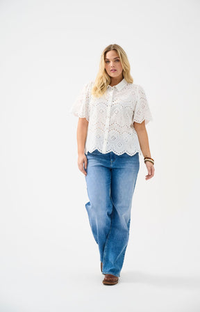 Woman wearing a white lace blouse and blue jeans on a white background