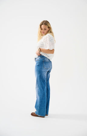 Woman wearing blue jeans and a white top on a white background