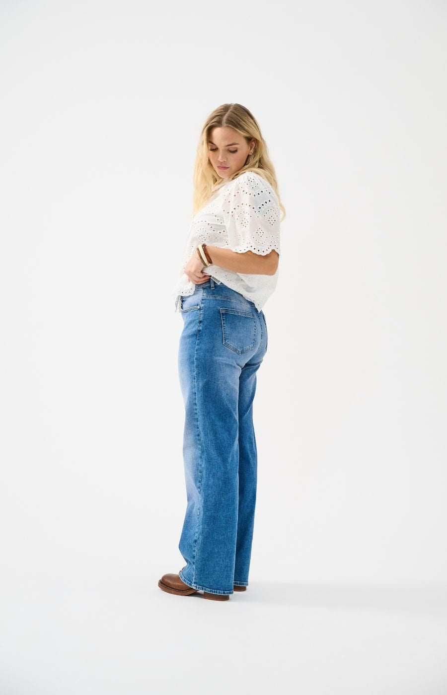 Woman wearing blue jeans and a white top on a white background