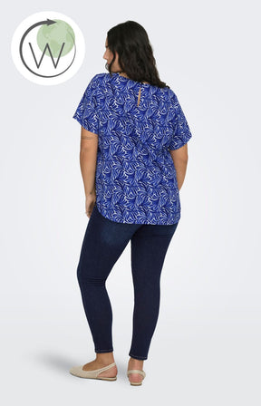 Woman wearing a blue patterned Vica top and dark jeans on a white background