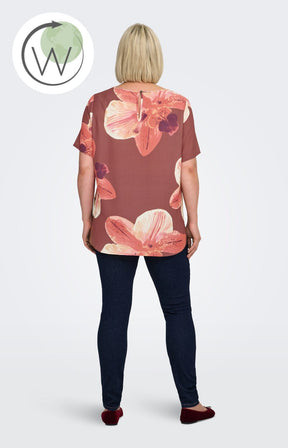 Woman wearing a rust colour, floral Vica blouse with dark jeans against a white background